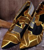 Handmade African Kivu Heels with black, gold, and white geometric patterns, placed on wood and stone background.