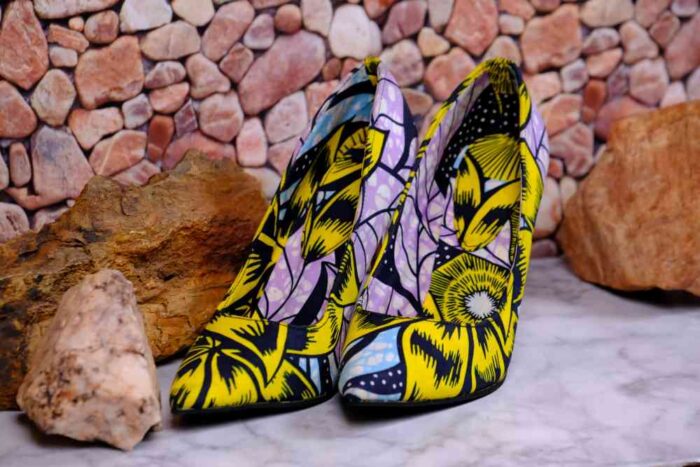 Handmade African Nyota Heels with yellow, black, purple, and blue floral patterns, placed on marble with stone accents.
