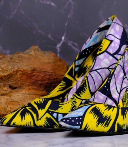 Handmade African Nyota Heels with yellow, black, purple, and blue floral patterns, placed on marble with stone accents.