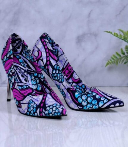 Handmade African Zuba Heels with abstract purple, blue, and black patterns, placed beside a drum and plant on a marble-like surface.