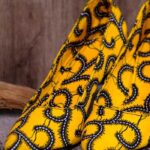 Handmade yellow and black swirl high-heeled shoes on a textured surface.