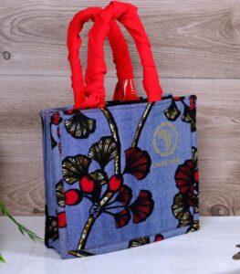 Denin Blossom Top-Handle Bag featuring bold orange feather print and hand-beaded floral appliqué with sequins, inspired by African Kente design.