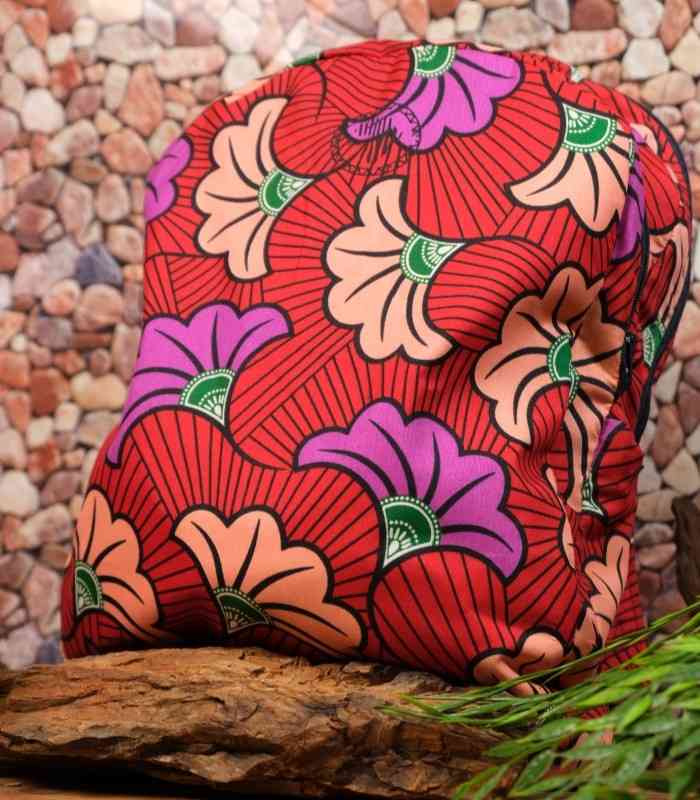 Flora Ankara Backpack with peach and violet floral motifs on a red background, accented with green details and L’Africaine Boutique logo.