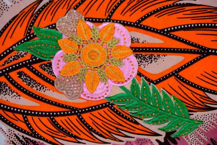 Desert Mirage Clutch featuring bold orange feather design and hand-beaded floral appliqué with sequins, inspired by the Vaal region.