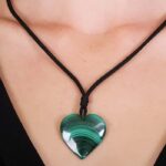 Heart-shaped green malachite pendant on a black cord, showcasing natural swirling patterns.