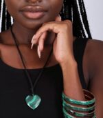 Heart-shaped green malachite pendant on a black cord, showcasing natural swirling patterns.