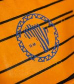 Heritage Kente Backpack with vibrant geometric Kente patterns in yellow, green, blue, and black, featuring L’Africaine Boutique logo.