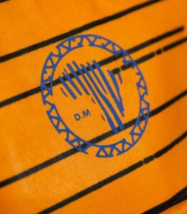 Heritage Kente Backpack with vibrant geometric Kente patterns in yellow, green, blue, and black, featuring L’Africaine Boutique logo.
