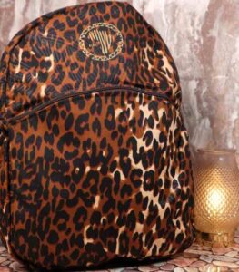 Leopard Luxe Backpack with golden brown and black leopard print, sleek silhouette, front pocket, and L’Africaine Boutique emblem.