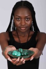 Three polished green malachite spheres in a matching decorative bowl, showcasing natural banding and elegant symmetry.