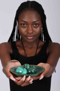 Three polished green malachite spheres in a matching decorative bowl, showcasing natural banding and elegant symmetry.