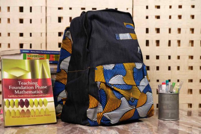 Midnight Geometry Ankara Backpack with black denim and geometric patterns in cobalt blue, golden yellow, and ivory, featuring L’Africaine Boutique logo.