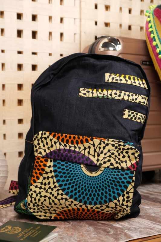 Plume Ankara Backpack with elongated teardrop motifs in teal, golden yellow, and amber orange on ivory, featuring L’Africaine Boutique logo.