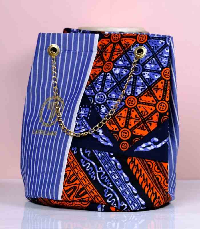 Sanaa African Cinch Bag 1 Sanaa African Cinch Bag made from Ankara fabric with blue pinstripes, orange and navy “L’Africaine” motif, and gold chain strap.