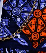 Sanaa African Cinch Bag made from Ankara fabric with blue pinstripes, orange and navy “L’Africaine” motif, and gold chain strap.