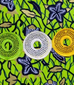 The Aura African Clutch in green Ankara fabric with floral and leafy print, featuring yellow, lime, and white embroidered sequin rings.