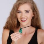 Teardrop-shaped green malachite pendant with natural banding on a black cord, symbolizing healing and emotional release.