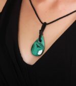 Teardrop-shaped green malachite pendant with natural banding on a black cord, symbolizing healing and emotional release.