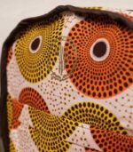 Sola Backpack with vibrant African wax print featuring concentric circles in orange, yellow, terracotta, and cream on durable canvas.