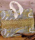 The Terra Tote Bag made from Ankara fabric with gold and white swirl design, golden embroidery, and padded cream handles.