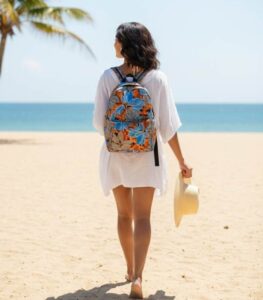 Tropical Bloom Backpack with vivid blue petals and fiery orange leaves on a grey and black background, featuring L’Africaine Boutique logo.
