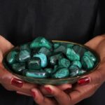 Decorative dish filled with 13 polished malachite stones of various sizes and shapes, showcasing rich green tones and natural banding.