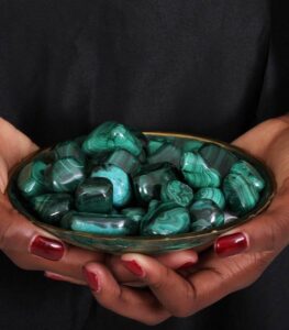 Decorative dish filled with 13 polished malachite stones of various sizes and shapes, showcasing rich green tones and natural banding.