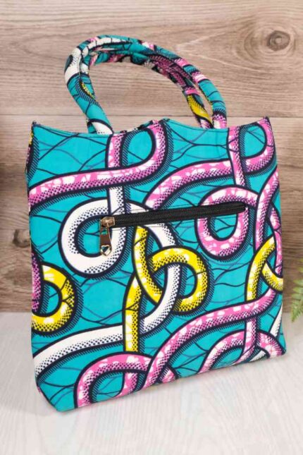 Ankara Tote Bag in turquoise wax fabric with bold pink, yellow, white, and black chain patterns, featuring padded handles and front zipper pocket.