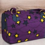 ankara star print handbag in deep purple and navy Ankara wax fabric with bold yellow and black star patterns, gold rings, and top zipper closure.