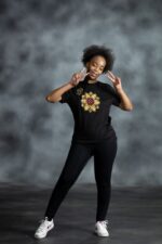 Floral Burst Tee with mandala-style flower appliqué in yellow, white, and red, accented by rhinestones on black cotton from L’Africaine Boutique.