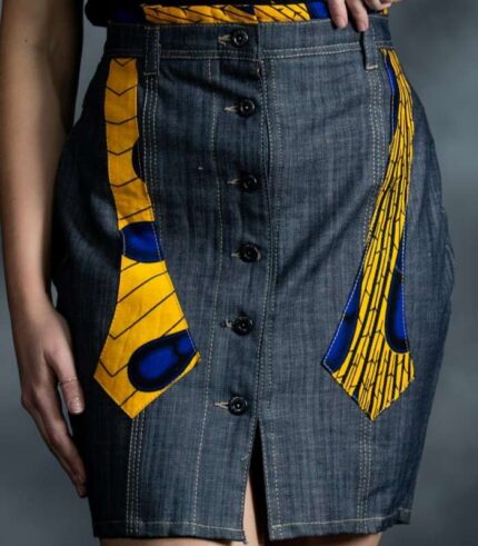 Slim grey-blue denim skirt with asymmetric button closure and muted Ankara accents on waistband and pockets.