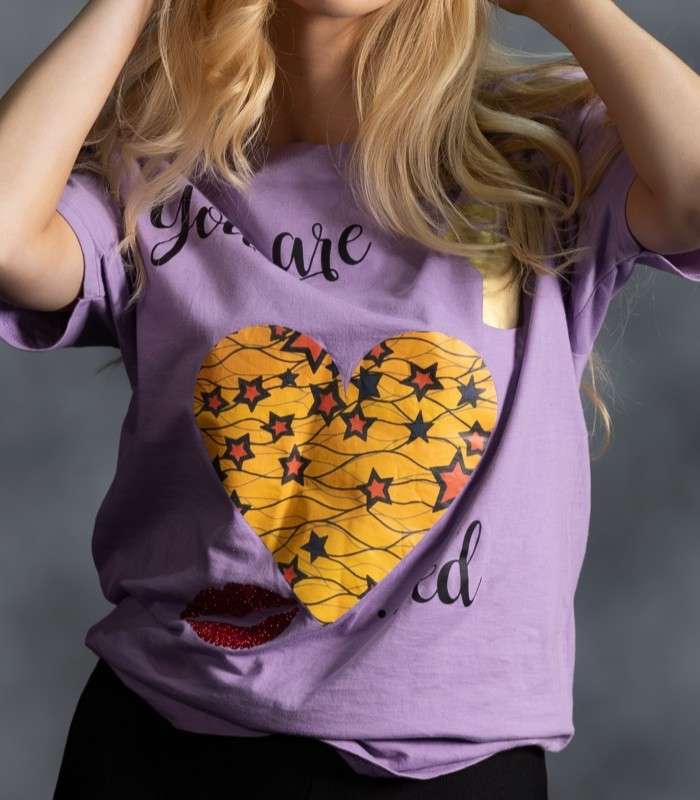 You Are Loved Lilac Tee 5 You Are Loved Lilac Tee with yellow African print heart, scattered stars, and red lips from L’Africaine Boutique.