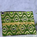 ankara gold wave clutch by L’Africaine Boutique—crafted from wax fabric with gold and green wave print, black detailing, and gold zipper for day or night.