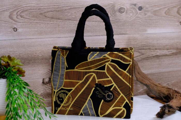 ankara golden noir handbag in black and golden-brown Ankara wax fabric with feather-like motifs, padded black handles, structured silhouette, and handcrafted front accent.