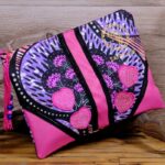 ankara heart tassel clutch in purple and black Ankara wax fabric with fuchsia leather frame, pink heart appliqués, and beaded tassel zipper pull.