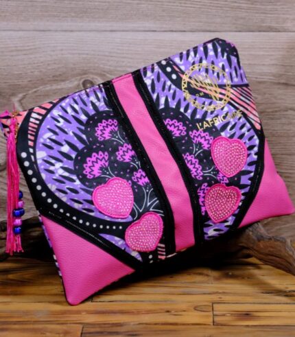 ankara heart tassel clutch in purple and black Ankara wax fabric with fuchsia leather frame, pink heart appliqués, and beaded tassel zipper pull.