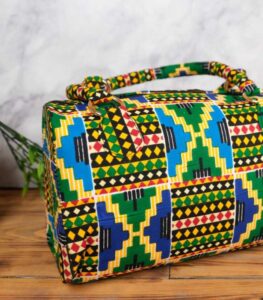 Ankara kente motif handbag in multicolor Ankara wax fabric with Kente-inspired geometric patterns, padded handles, gold rings, and top zipper closure.