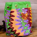 ankara sequin bucket bag in multicolor Ankara wax fabric with zigzag print, green faux leather trim, gold chain strap, and sequin bow embellishment.