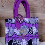 ankara violet spiral handbag in vivid violet Ankara wax fabric with black, white, and lilac spiral motifs, padded handles, and sequined butterfly accent.
