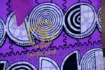 ankara violet spiral handbag in vivid violet Ankara wax fabric with black, white, and lilac spiral motifs, padded handles, and sequined butterfly accent.